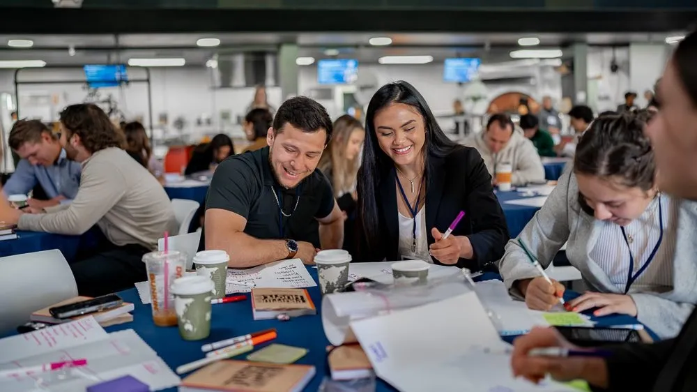Students engaged in group study and note-taking at a table with coffee cups in an academic support setting at Menlo College.